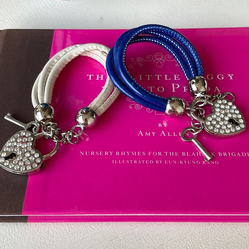 Two lock and key bracelets, one blue and one white banded. Rhinestone details